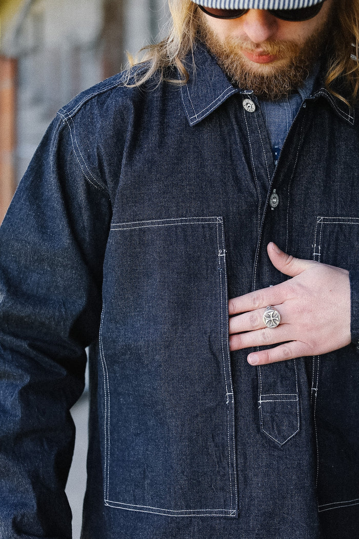 Man wearing a dark denim jacket with a blurred background