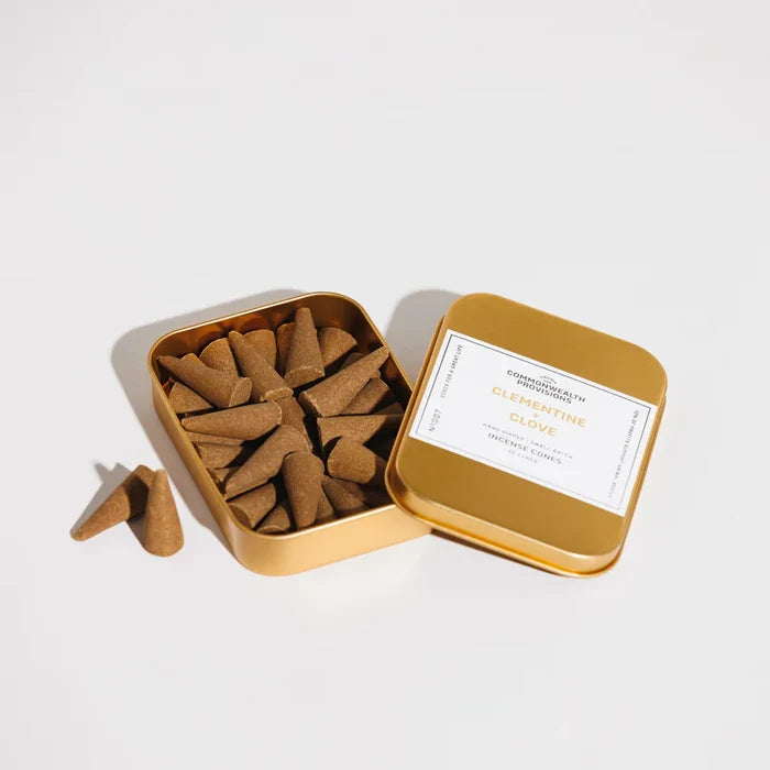 Gold tin of Clementine and Clove incense cones with two cones beside it on white background from Iron Shop Provisions