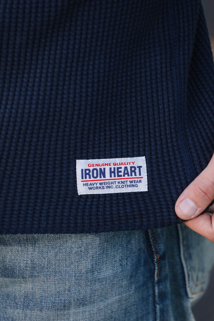 Navy blue garment with Iron Heart label held by a hand