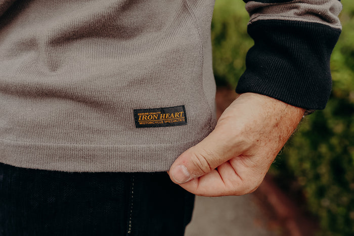 Close-up of Iron Heart motorcycle sweatshirt label on taupe fabric with black cuff seen outdoors