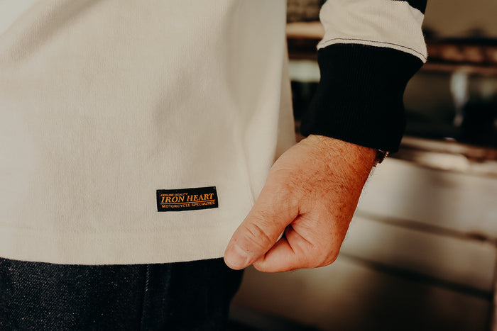 Close-up of a beige Iron Heart branded shirt cuff with black sleeve detail worn by a person