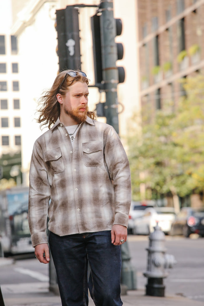 Man wearing a plaid shirt and sunglasses on a city street