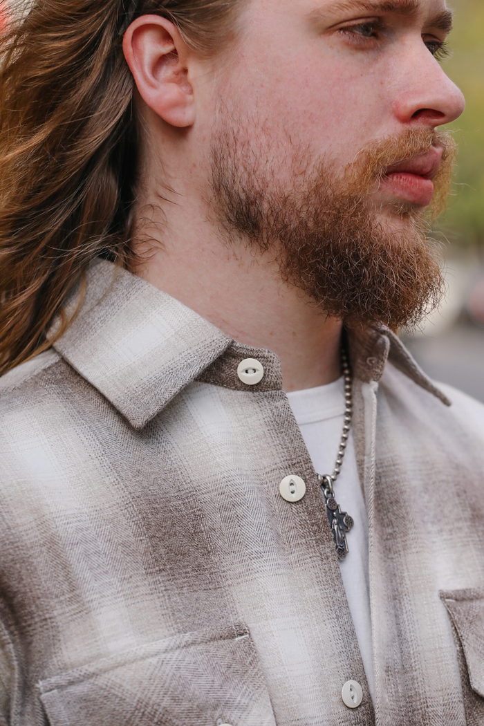 Man wearing a plaid shirt with a focus on the collar and buttons.