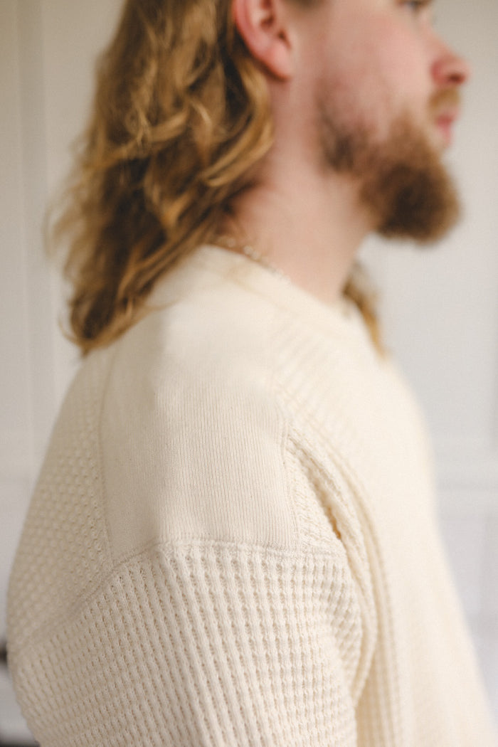 Man wearing a beige sweater against a plain background