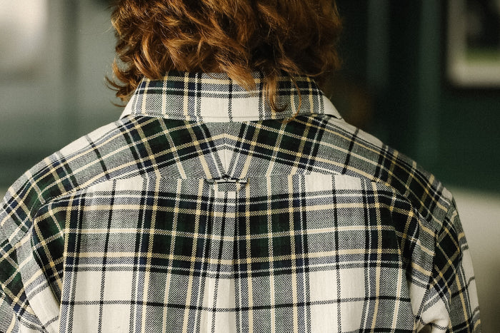 Person wearing a plaid shirt with a blurred background