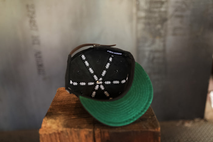Black and green cap on a wooden block with a textured background
