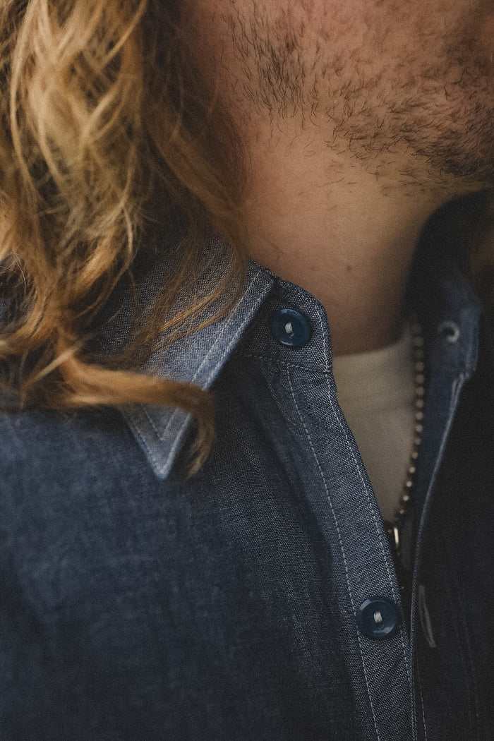 Close-up of a person wearing a dark denim jacket with a blurred background