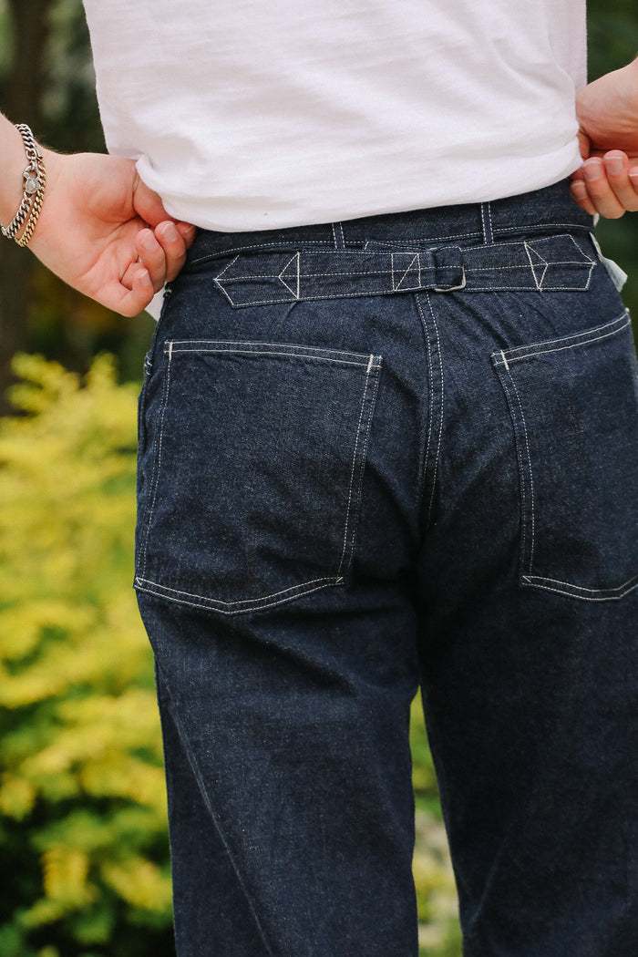 Person wearing dark blue jeans with a blurred green background