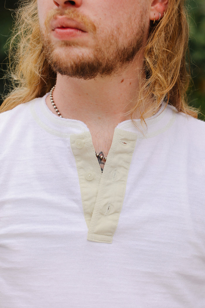Close-up of a person wearing a white shirt with a beige collar.