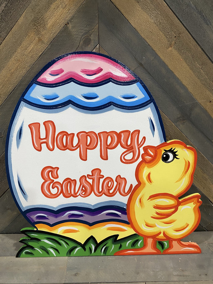 Happy Easter egg sitting on grass with little chick infront of it.