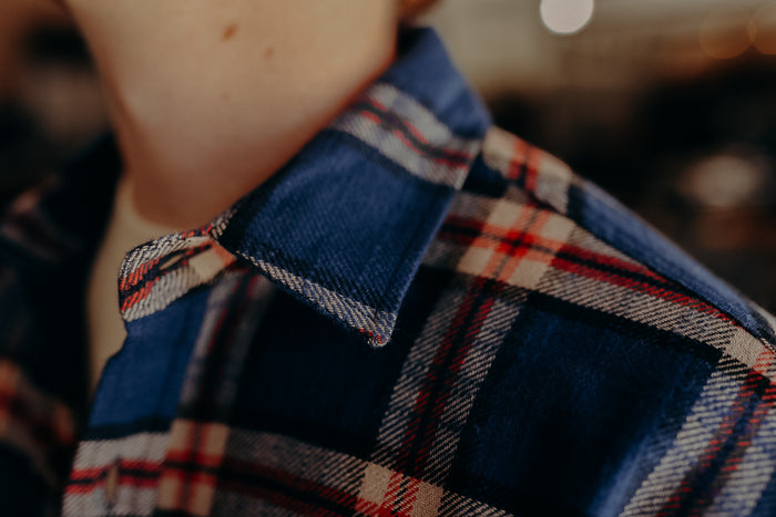 Close-up of blue and red plaid flannel shirt collar on person wearing a white undershirt