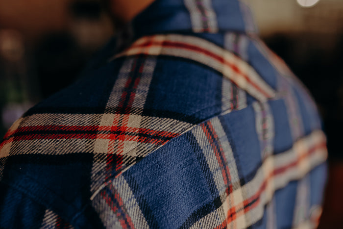 Close-up of blue and red plaid flannel shirt shoulder detail at Iron Shop Provisions