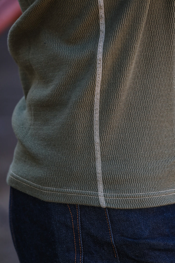 Close-up of a green jacket with a zipper and blue jeans.