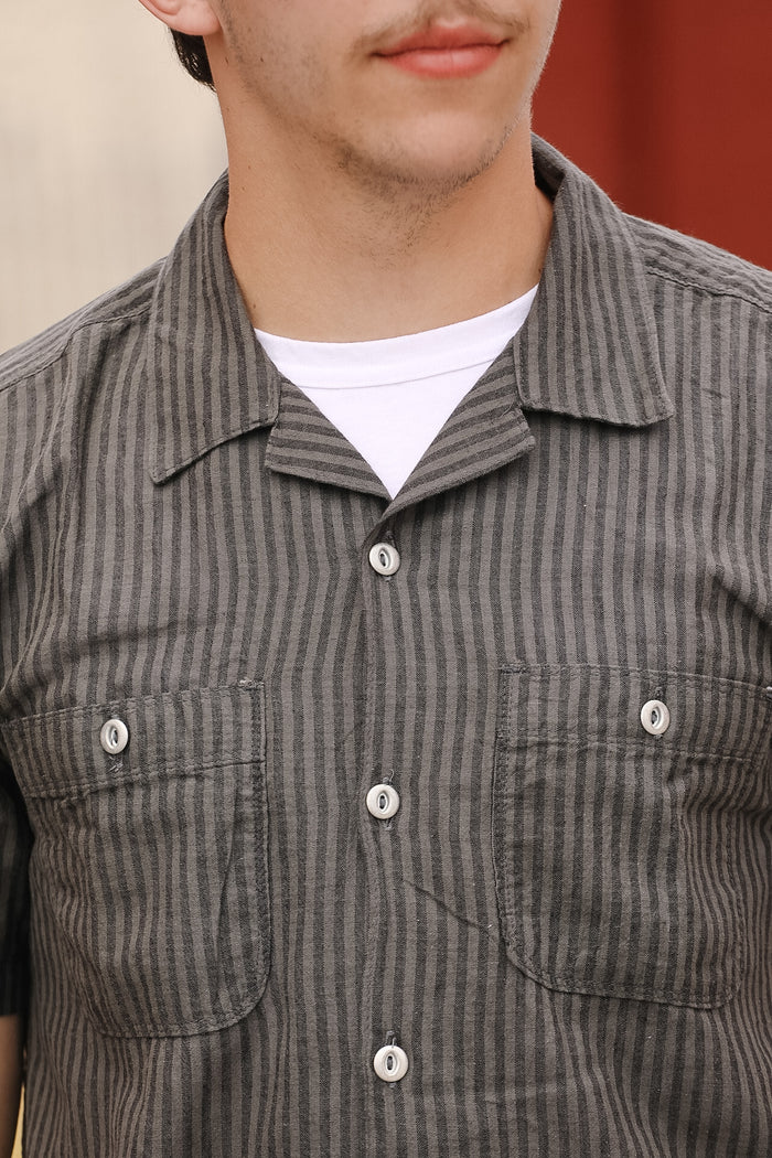 Close-up of a person wearing a gray striped shirt with a white collar.