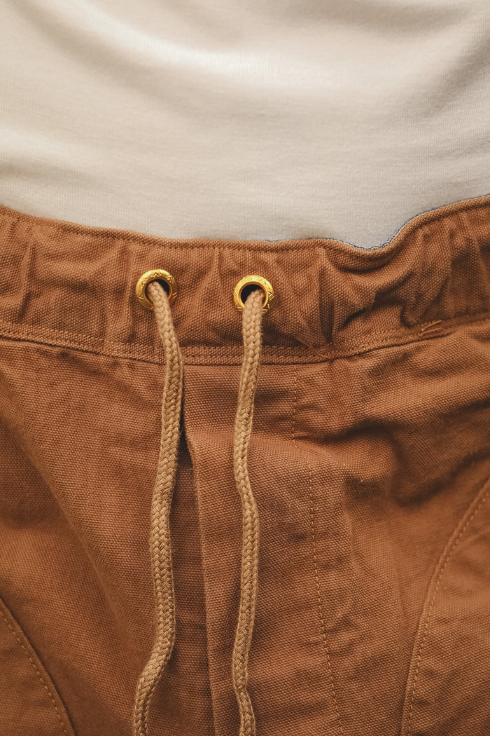 Close-up of brown pants with drawstring and beige shirt in the background