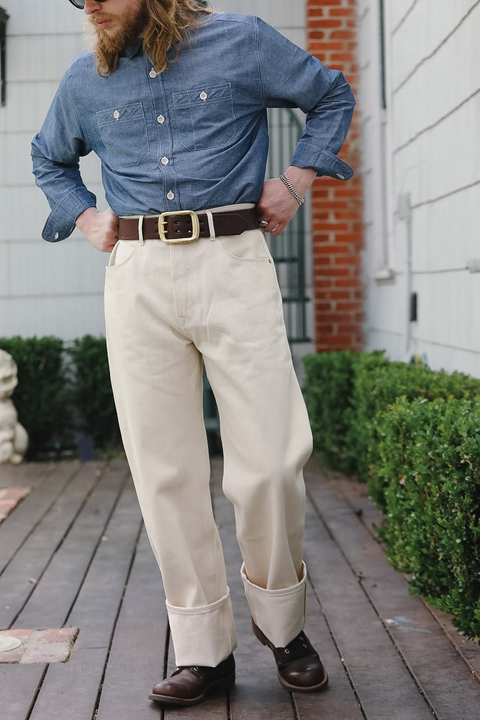 Person wearing a blue shirt, beige pants, and brown shoes on a wooden deck.