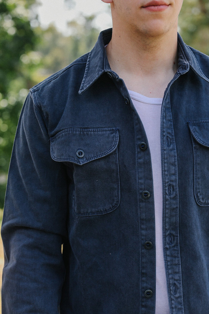 Close-up of man wearing a faded black button-up shirt over a white t-shirt outdoors