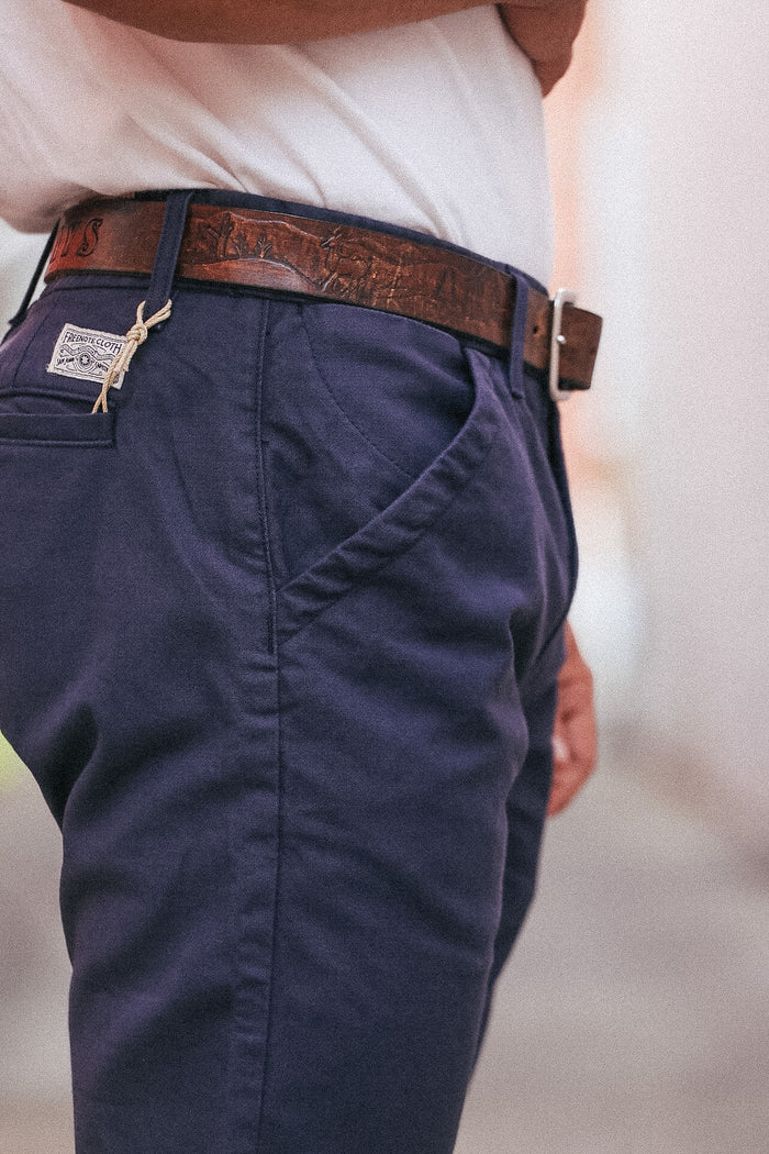 Navy pants with a brown belt and visible brand logo on a blurred background