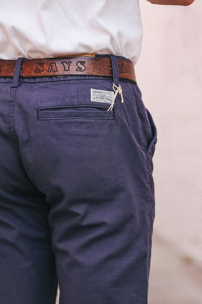 Navy pants with a brown belt and 'SAYS' logo on a light background
