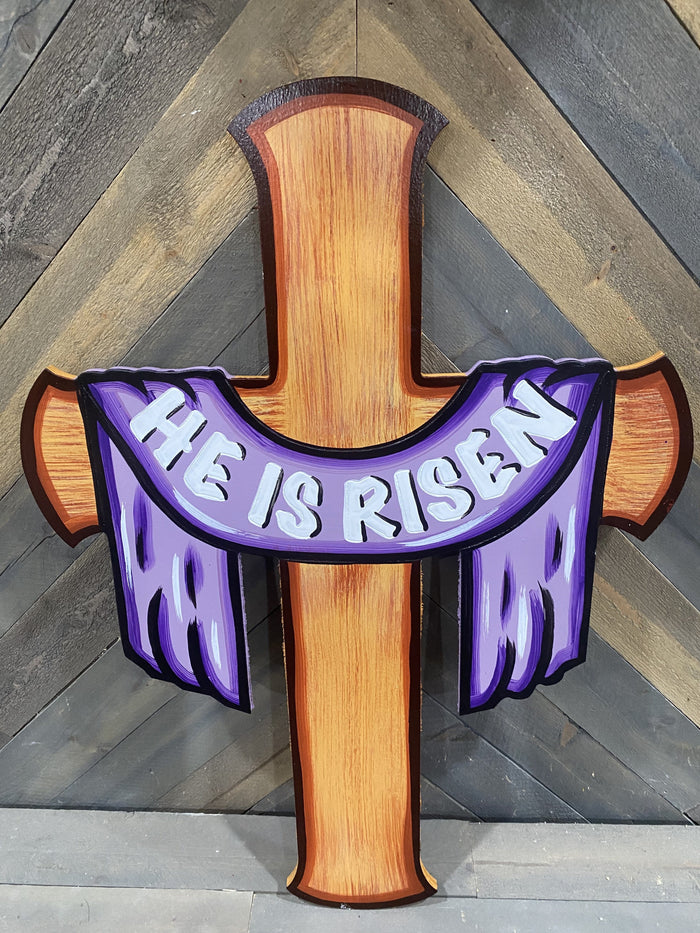 He is risen on a purple scarf draped scross a painted wooden cross
