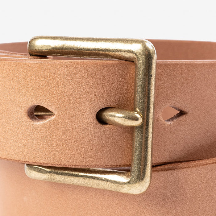 Close-up of a tan leather belt with a square brass buckle from Iron Shop Provisions
