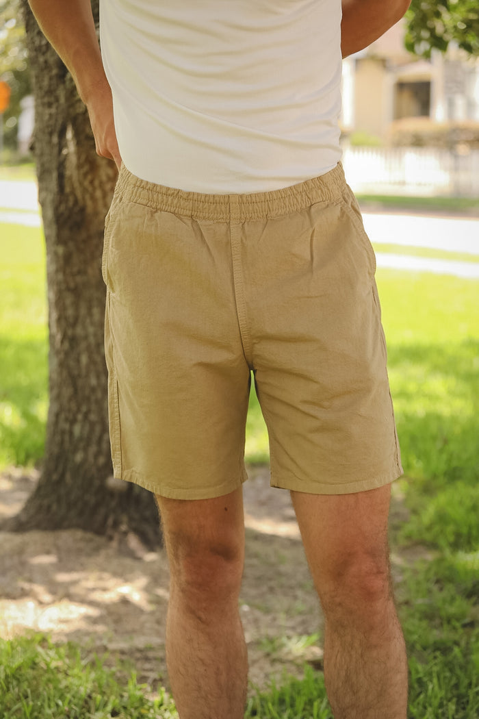 Person wearing beige shorts and a white shirt in an outdoor setting