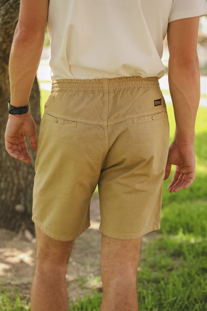 Person wearing beige shorts and a white shirt in an outdoor setting