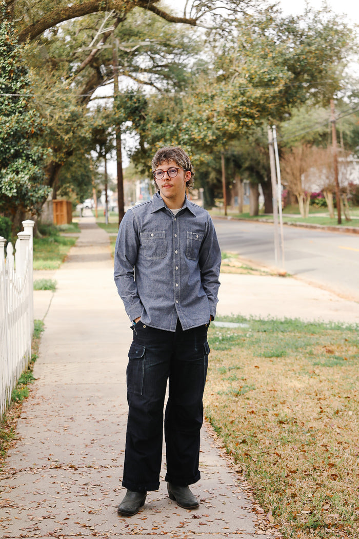 Person standing on a sidewalk with trees and grass in the background
