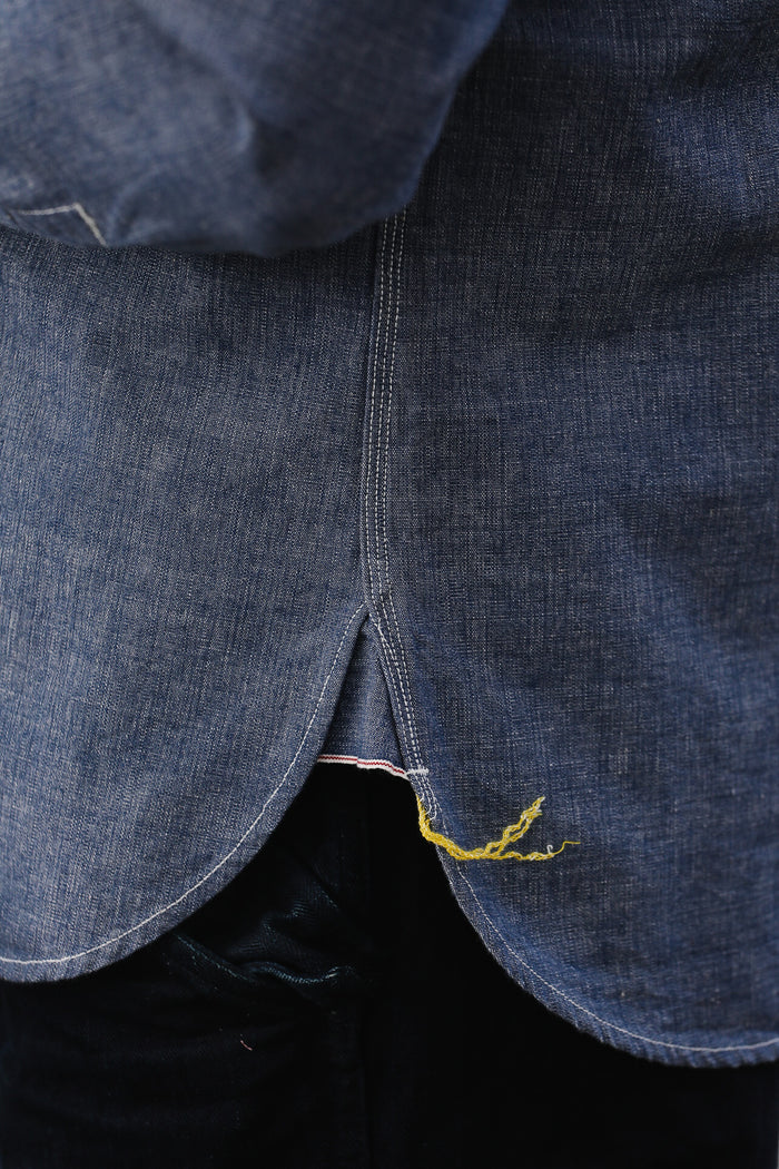 Close-up of a blue denim fabric with a yellow thread, possibly indicating a repair or stitching detail.