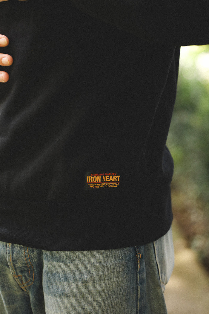 Person wearing a black jacket with 'Iron Heart' logo, blurred background