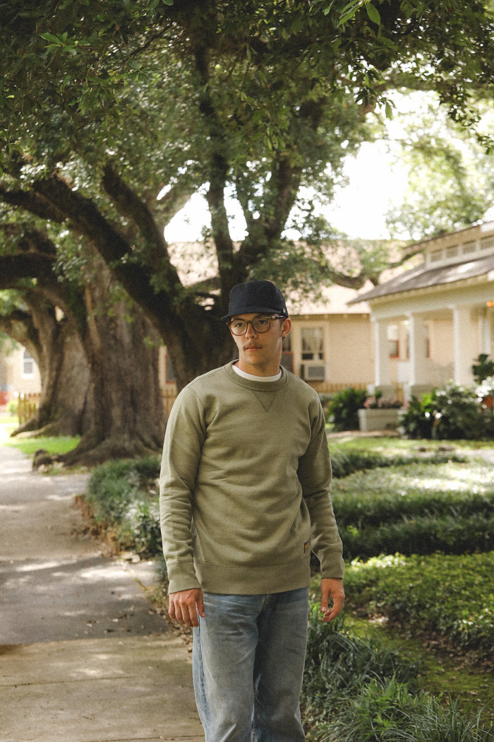 Man standing on a sidewalk with trees and a house in the background