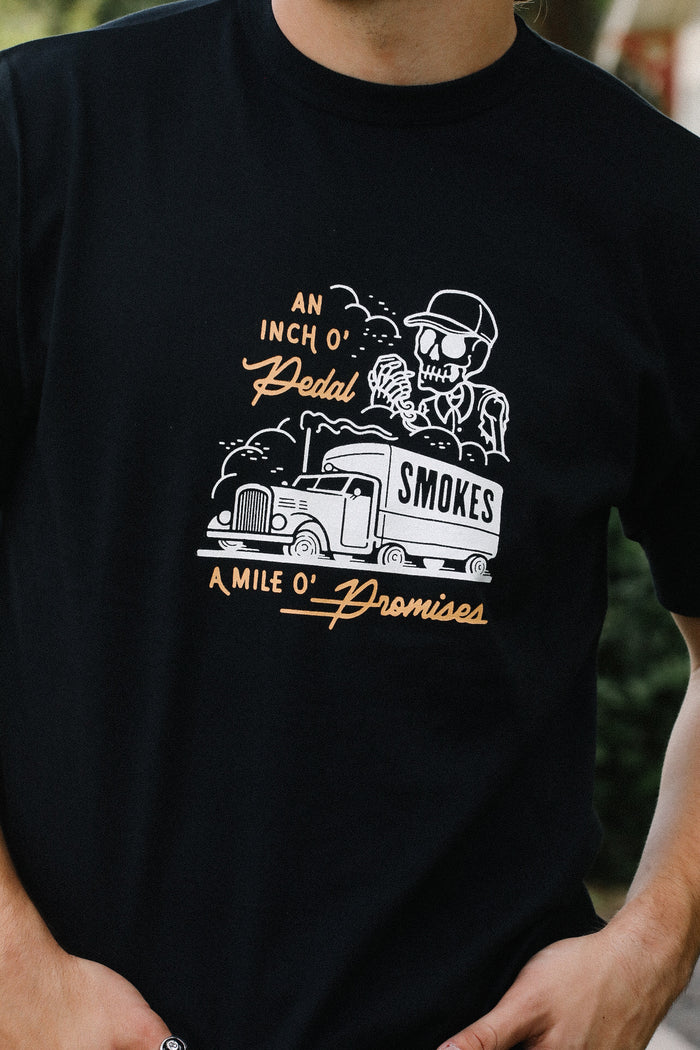 Black tee with skeleton driver graphic and vintage truck labeled 'SMOKES' with text An Inch O' Pedal A Mile O' Promises