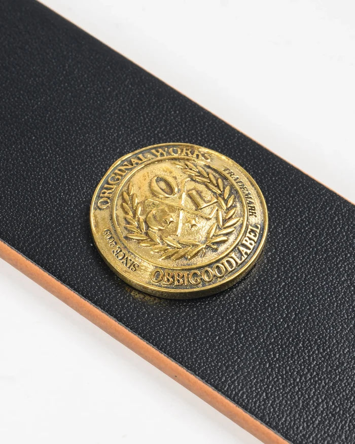 Brass coin with engraved design on a black leather case