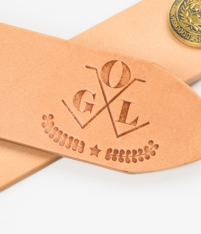 Leather strap with 'GOL' engraving on a white background