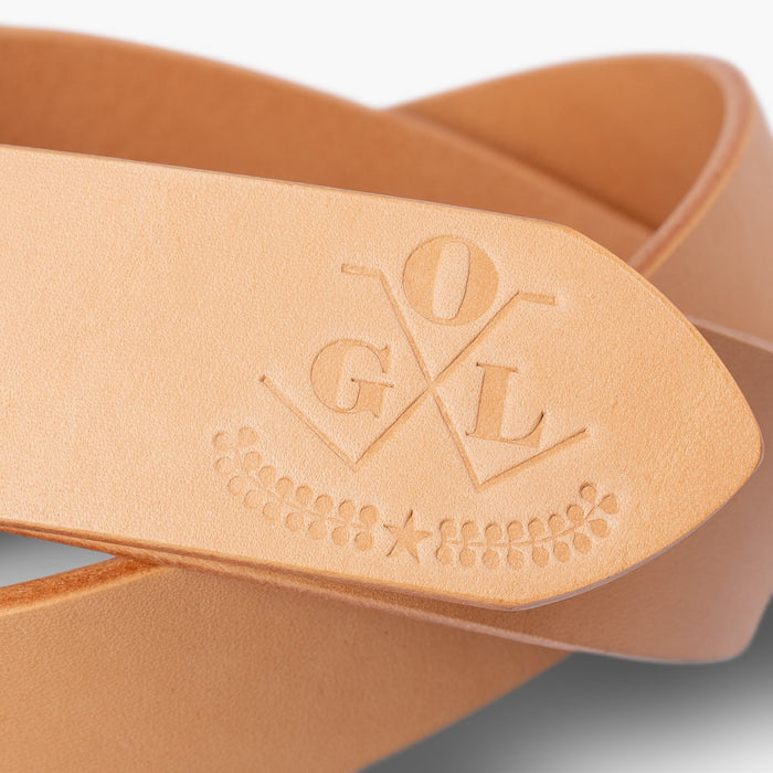 Close-up of natural leather belt with embossed OGL logo and decorative star and leaves detail