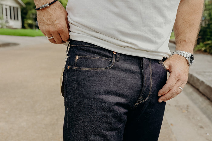 Close-up of man wearing dark denim jeans and white t-shirt, outdoor street background