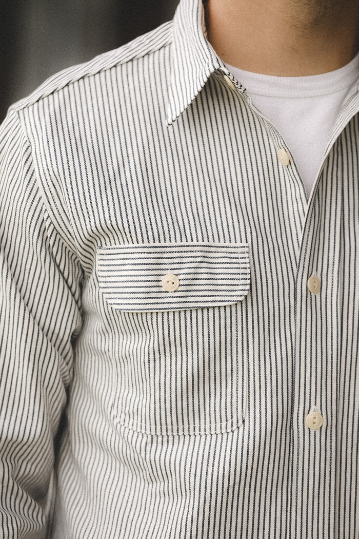 Close-up of a person wearing a striped shirt with a pocket and collar.