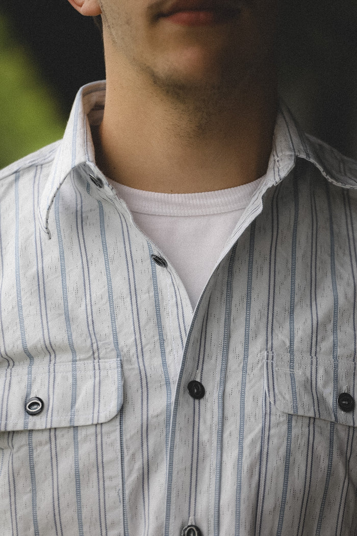 Close-up of a person wearing a striped shirt with a blurred background