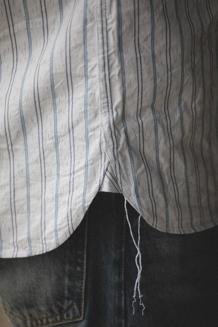 Close-up of a striped shirt with a pocket and dark pants.