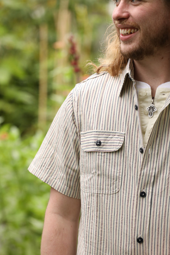 Man wearing a striped shirt with a blurred natural background