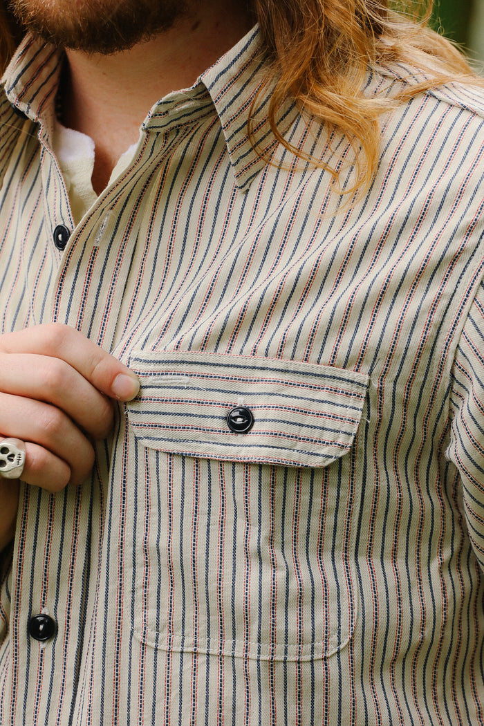 Close-up of a person wearing a striped shirt with a focus on the chest pocket.