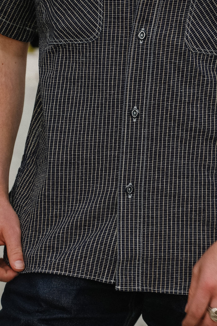 Close-up of a person wearing a black and white checkered shirt with a blurred background