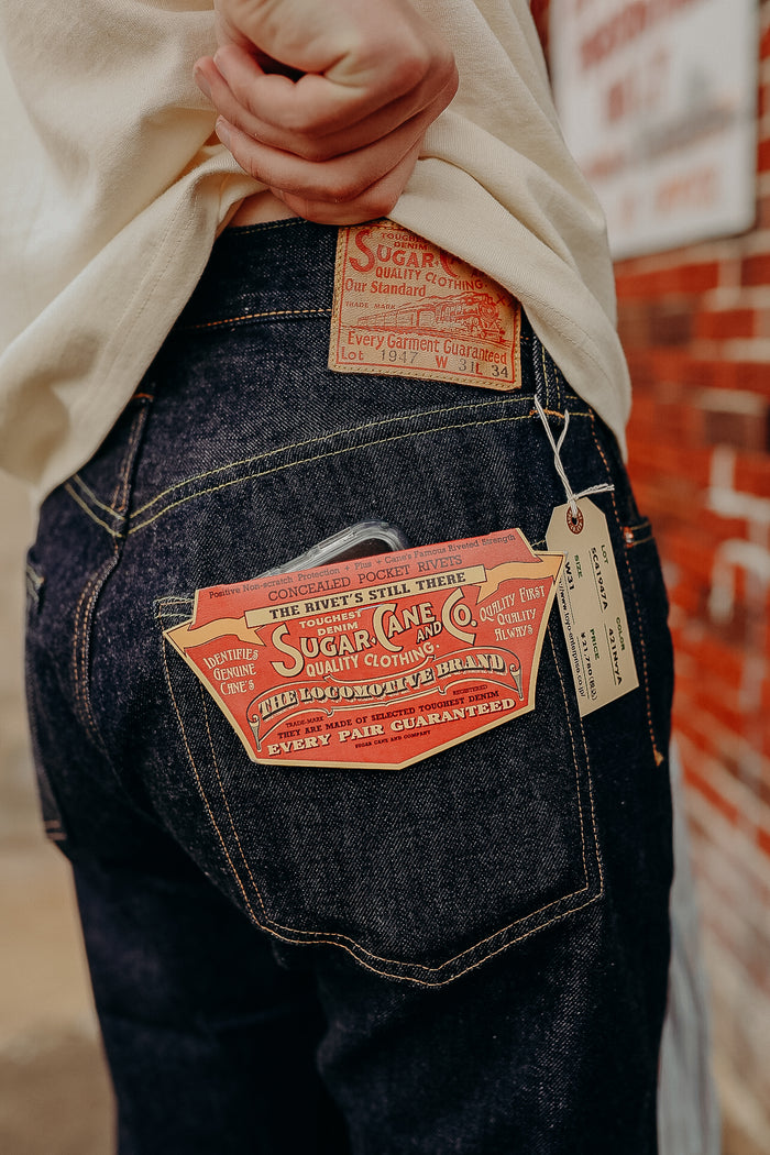 Close-up of dark denim Sugar Cane jeans with vintage branded labels and tags on back pocket