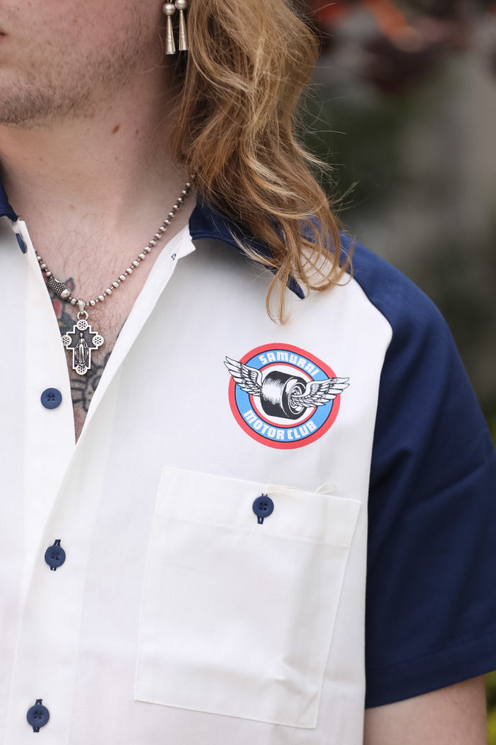 Close-up of a person wearing a white shirt with a logo on the chest.