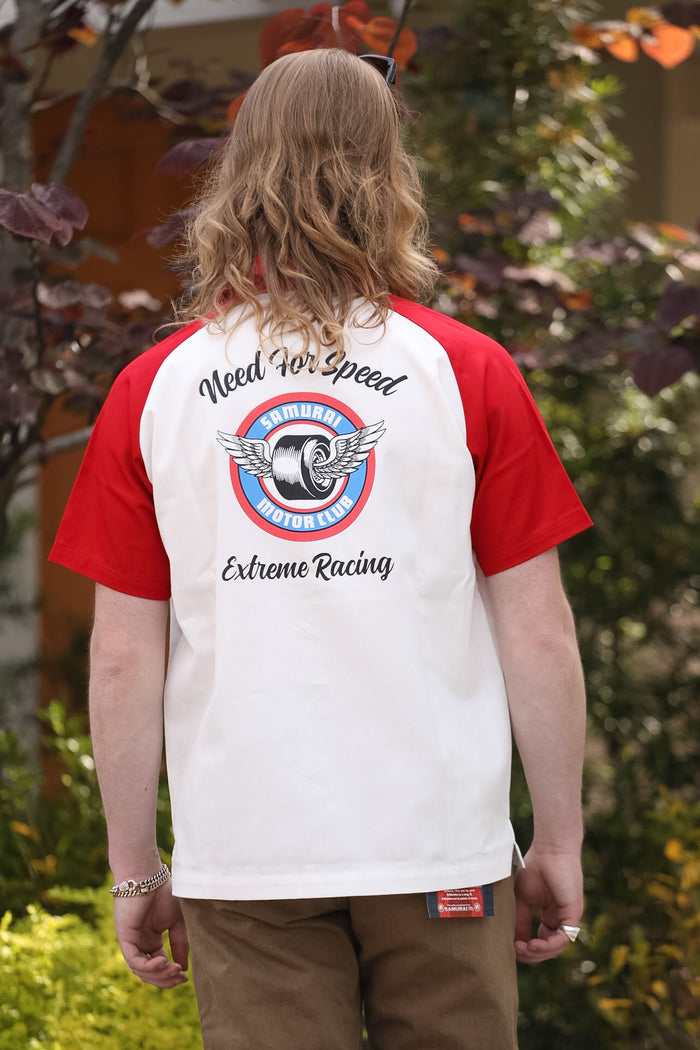 Person wearing a red and white t-shirt with 'Need For Speed Extreme Racing' design on the back, standing outdoors.