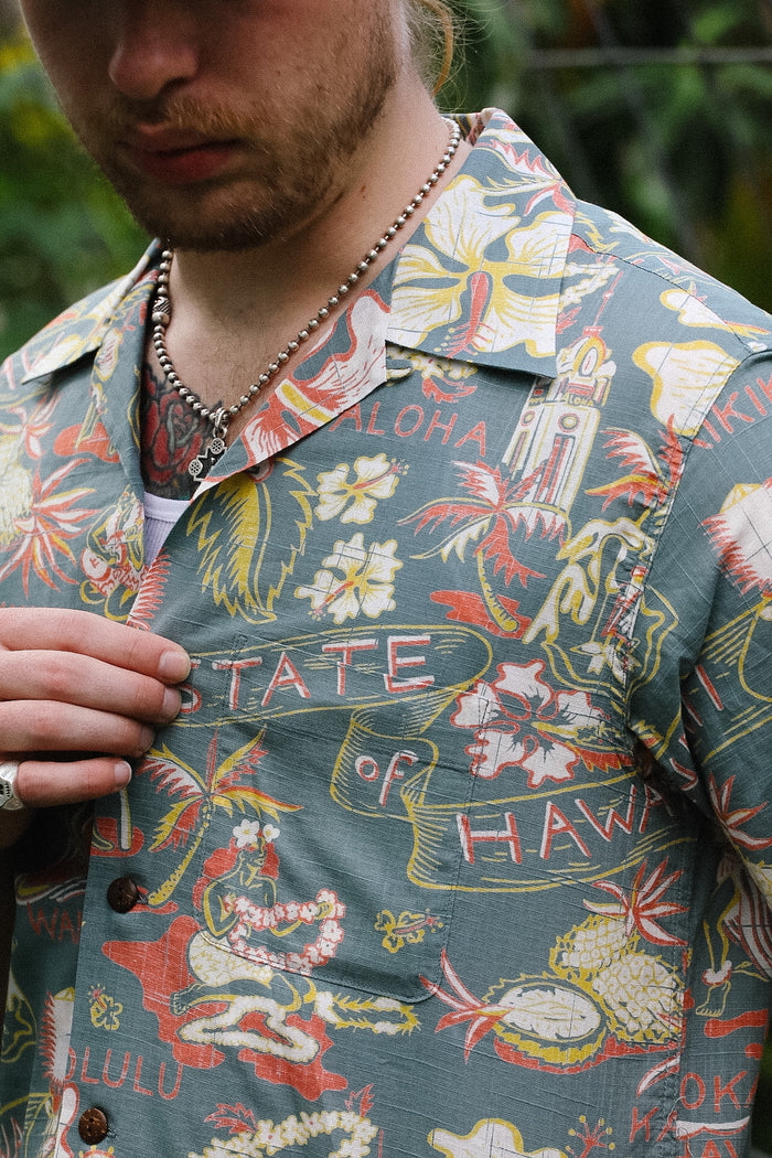 Person wearing a colorful Hawaiian shirt with floral and text patterns.