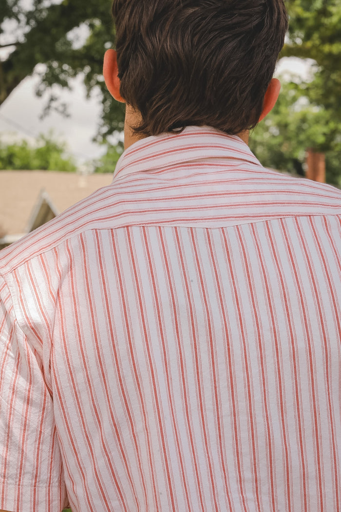 Person wearing a red and white striped shirt with a blurred outdoor background