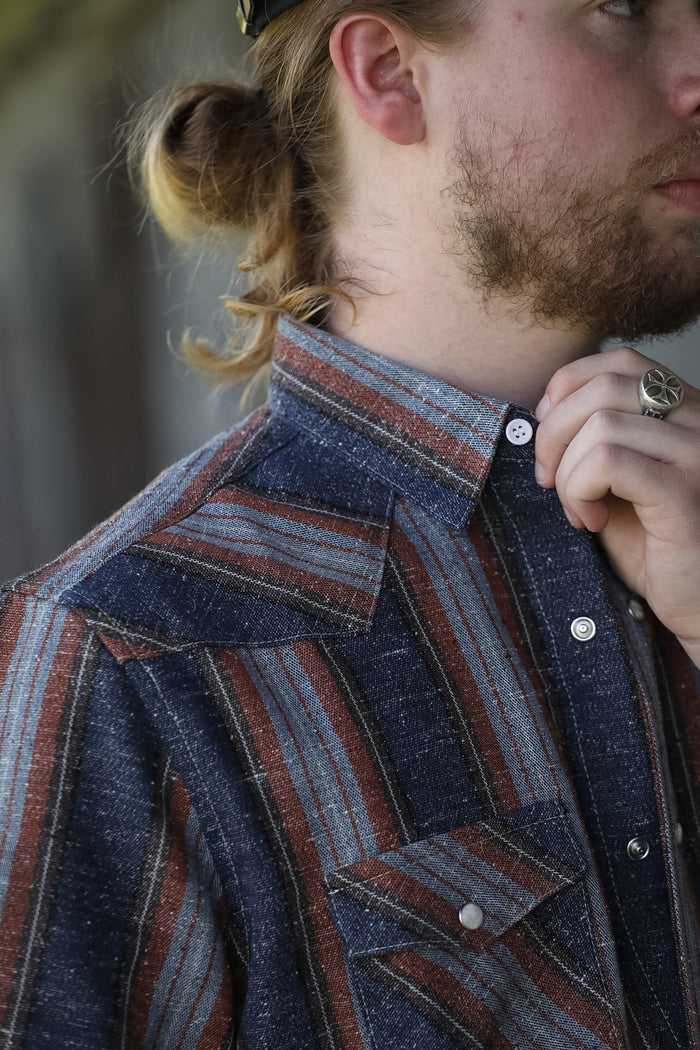 man wearing a stripe shirt standing in an industrial setting