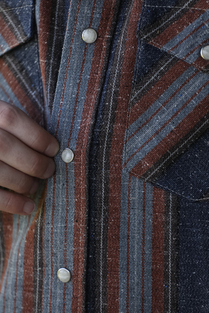 man wearing a stripe shirt standing in an industrial setting