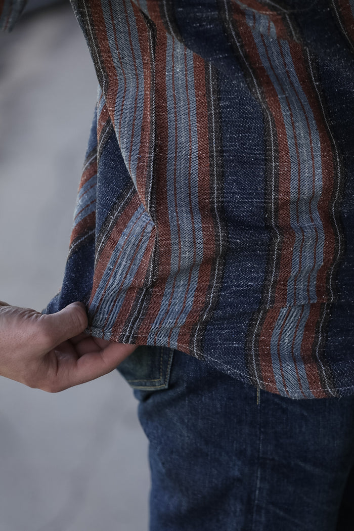 man wearing a stripe shirt standing in an industrial setting